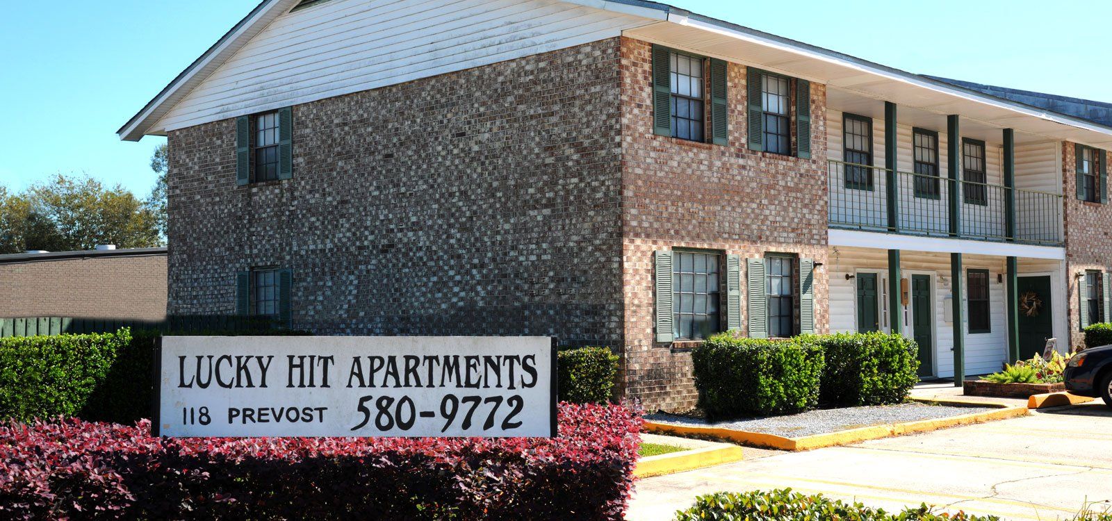 A brick apartment building with a sign that says lucky hit apartments