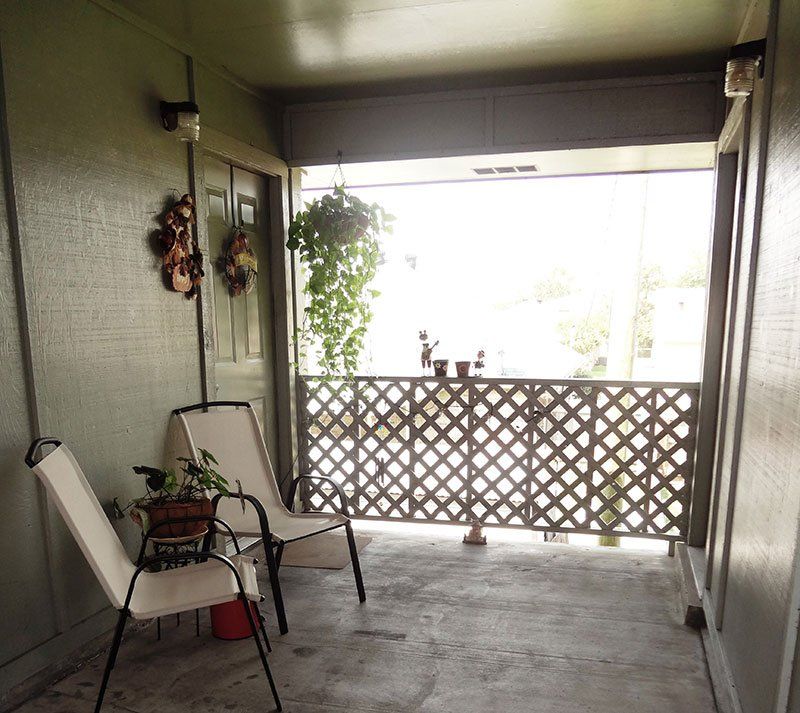 A porch with two chairs and a lattice railing