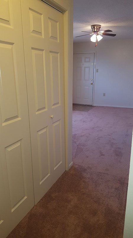 A hallway leading to a bedroom with a ceiling fan.