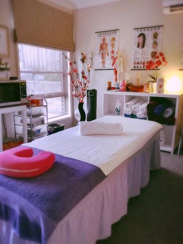 A massage table with a pink pillow on it