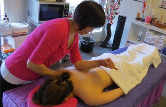 A woman in a pink shirt is giving a woman a massage