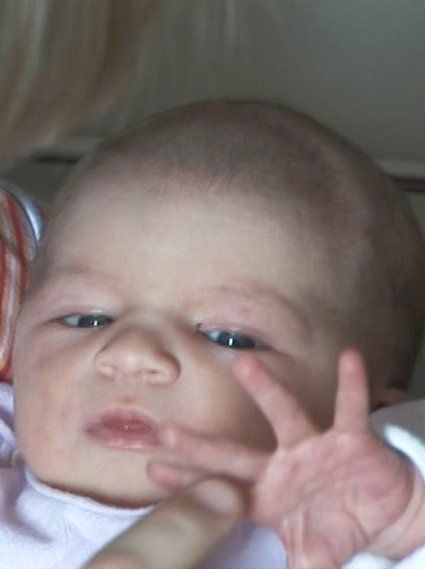 Ein wenige Stunden alter Säugling schaut auf den Finger seiner Mutter und versucht danach zu greifen.