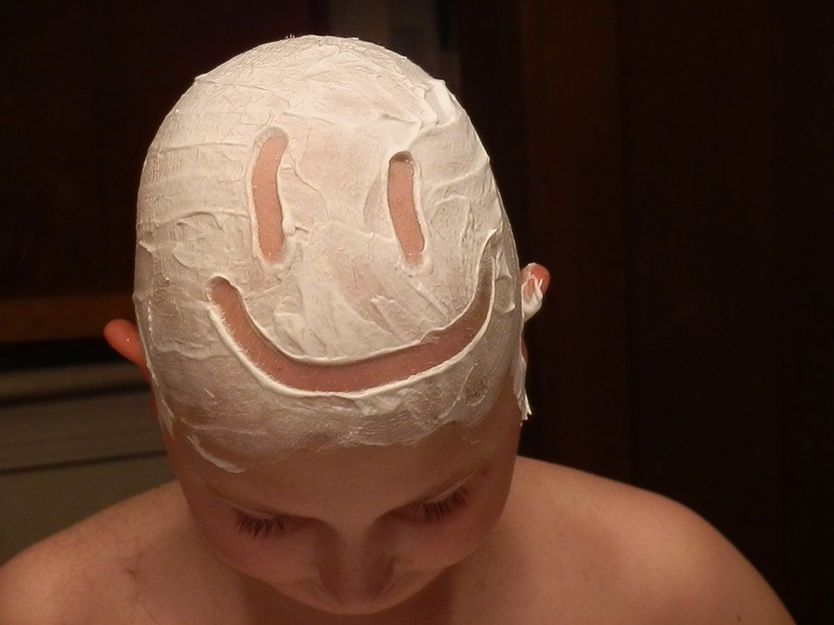 boy with shave cream shaped into smile on his head.