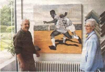 Ein Mann und eine Frau stehen vor einem Gemälde von Fußballspielern