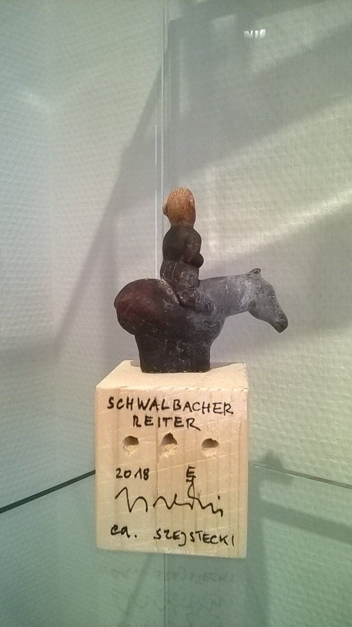 Eine Skulptur eines Mannes, der auf einem Holzblock auf einem Pferd reitet