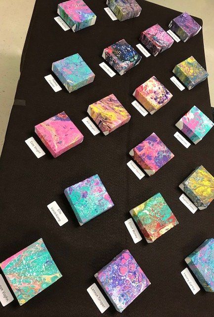 A bunch of small paintings are lined up on a table.