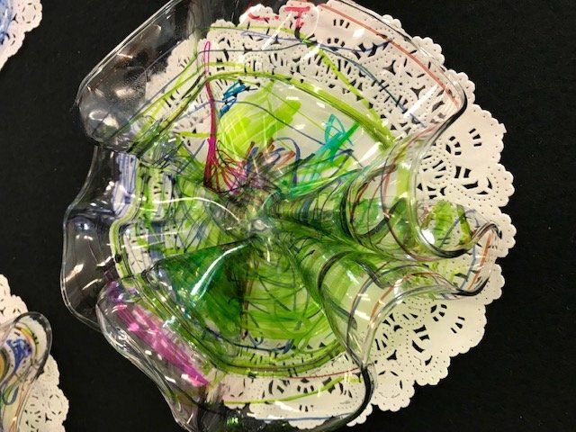 A plastic container with a drawing on it is sitting on a white lace napkin.