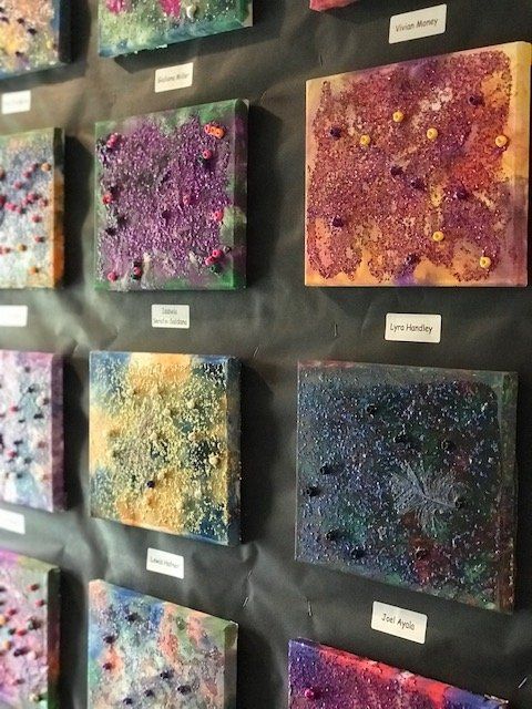 A row of colorful paintings are lined up on a wall