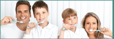 A family is brushing their teeth together and smiling
