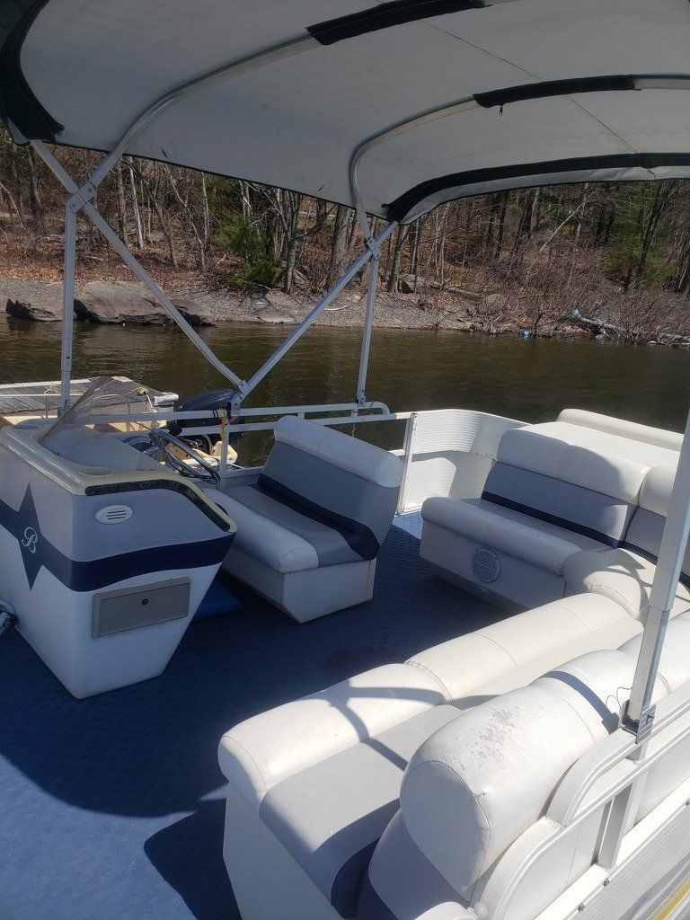 A pontoon boat is sitting on top of a body of water.