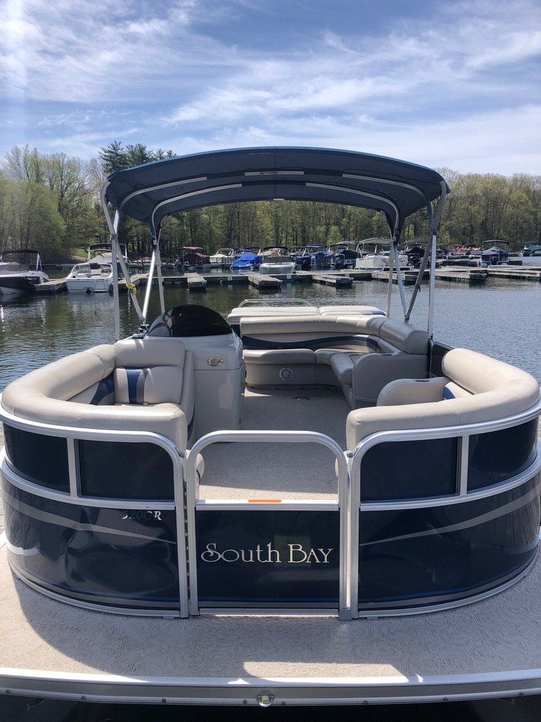A pontoon boat is docked in a marina on a lake.