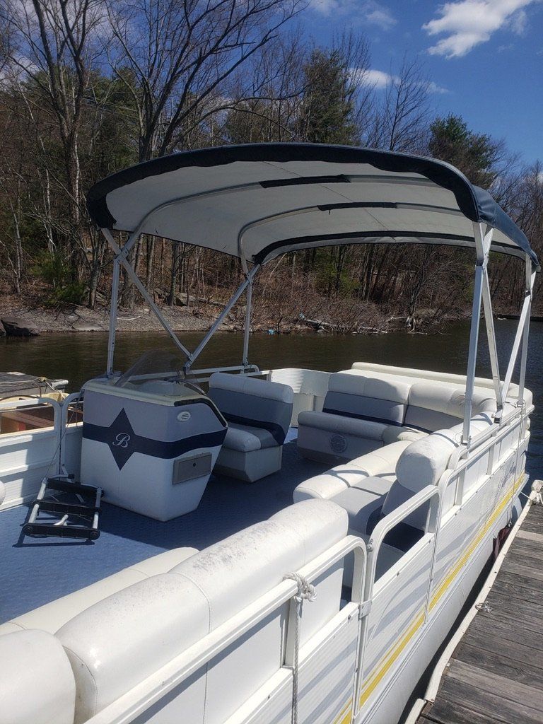 A pontoon boat is docked at a dock on a river.