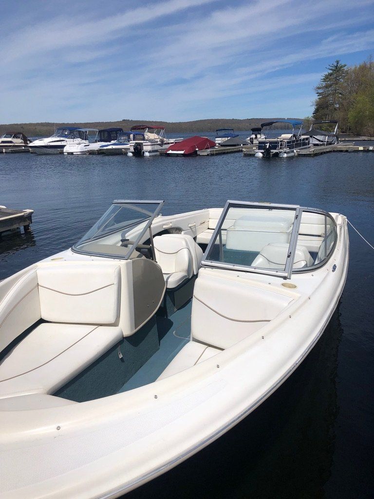 A white boat is docked in the water at a marina.