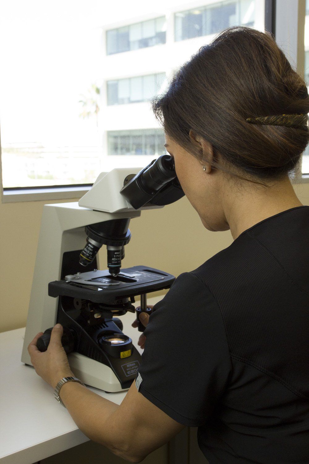 A nurse using a microscope for Mohs Micrographic Surgery