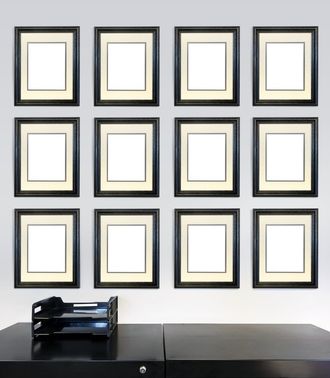 Twelve framed award certificates for employee of the month images on a wall in an office, in front of a file cabinet.