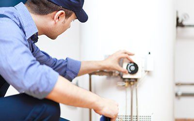 Technician adjusting a water heater thermostat Technician adjusting a water heater thermostat