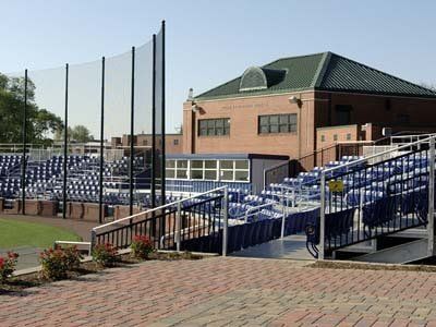 Baseball stadium with blue seats, brick exterior, and protective netting.
