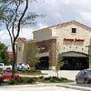 Building with stone facade and red accents, likely a retail location; cars in parking lot.