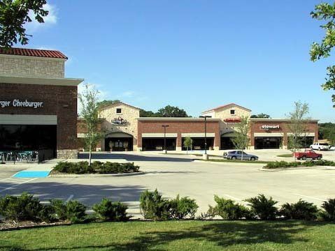Shopping center with stores and parking lot on a sunny day.