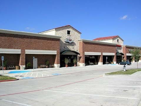 Exterior view of a brick commercial building with covered walkways, under a clear blue sky.