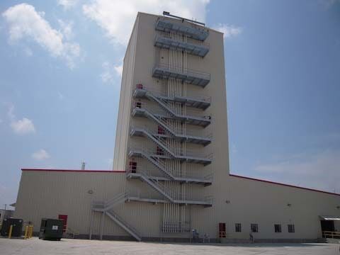 Tall industrial building with external metal staircases on a sunny day.