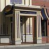 Ornate building entrance with beige pillars, blue awning, and sign.