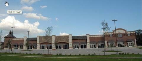 A strip mall with varying facade materials under a blue sky.