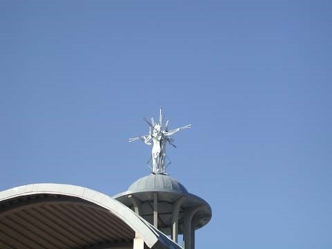 Silver statue of Jesus on a dome against a clear blue sky.