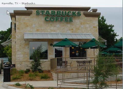Starbucks in Kerrville, TX: beige stone building, green sign, patio with green umbrellas.