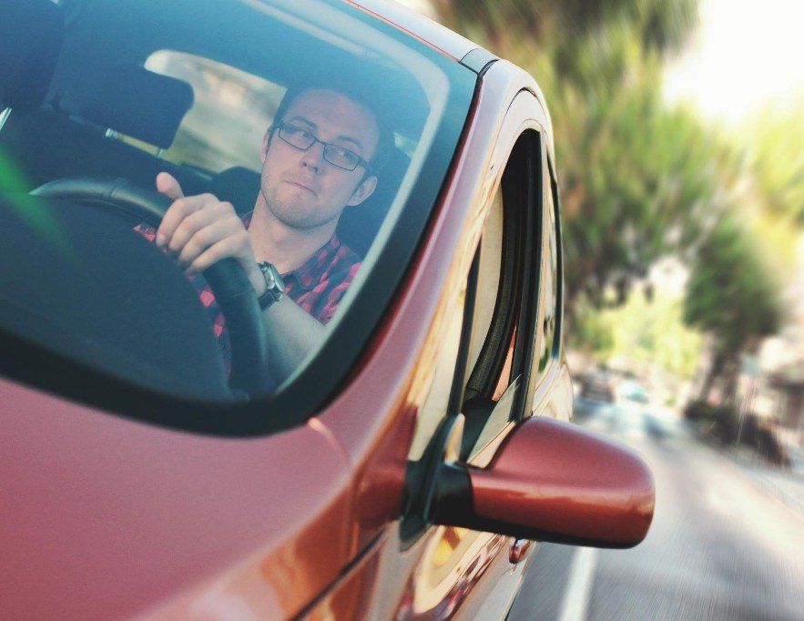 Gentleman driving a red car.