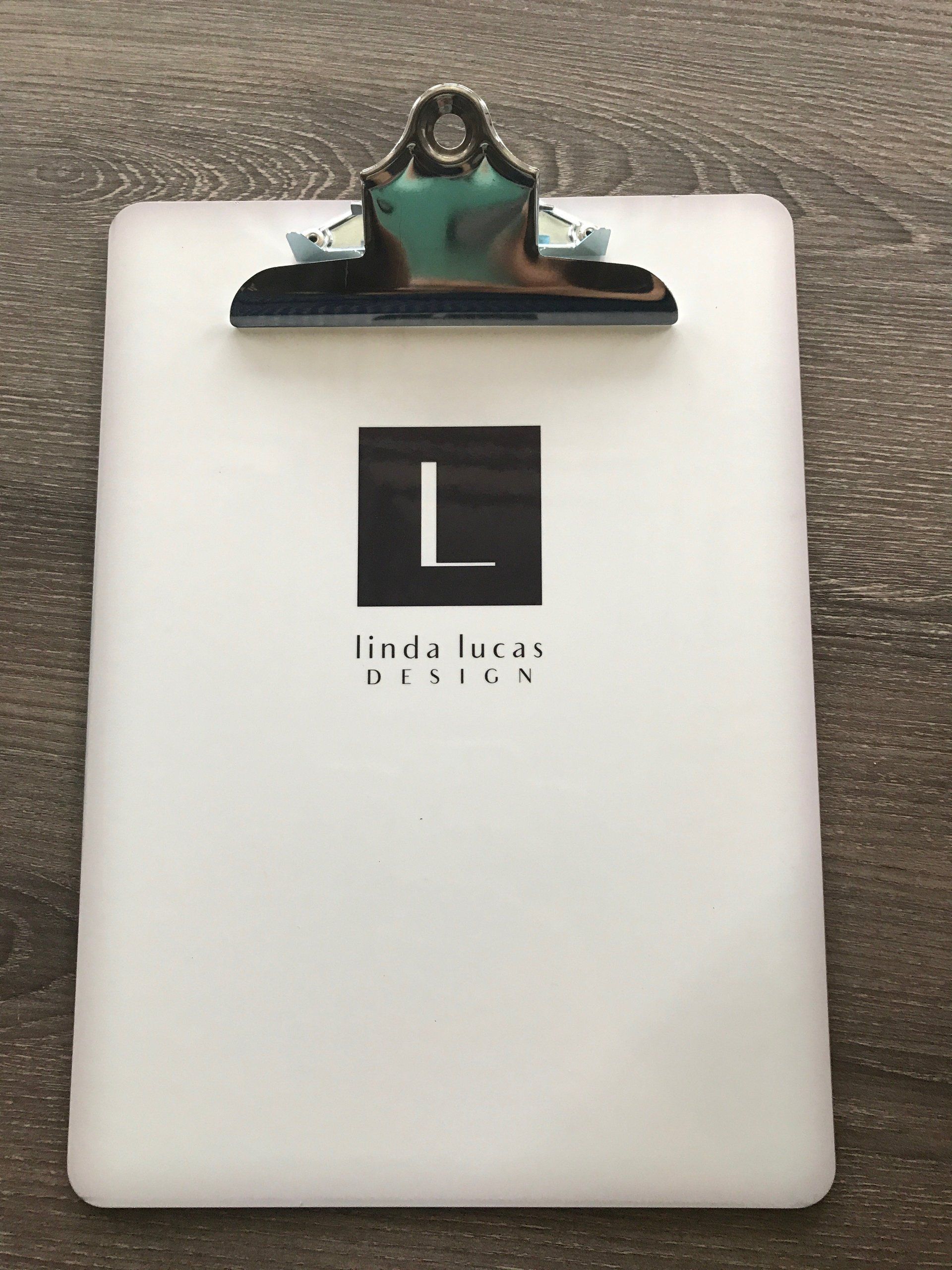 White clipboard with black clip and a black square logo with a white “L” on the front.