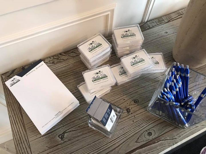 Stacked white notepads, blue pens, and small boxes arranged on a wooden table indoors