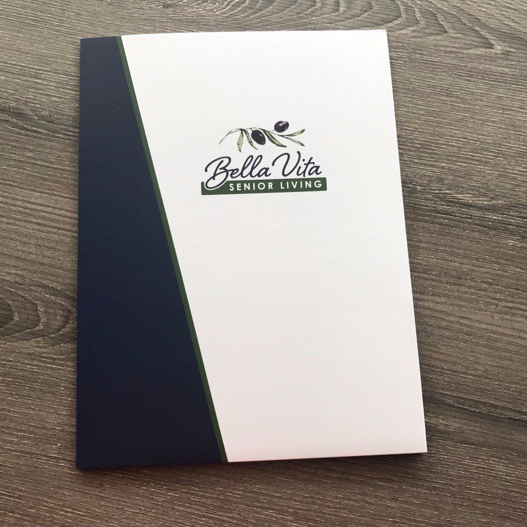 White and navy Bella Vita Senior Living brochure or booklet on a wood surface