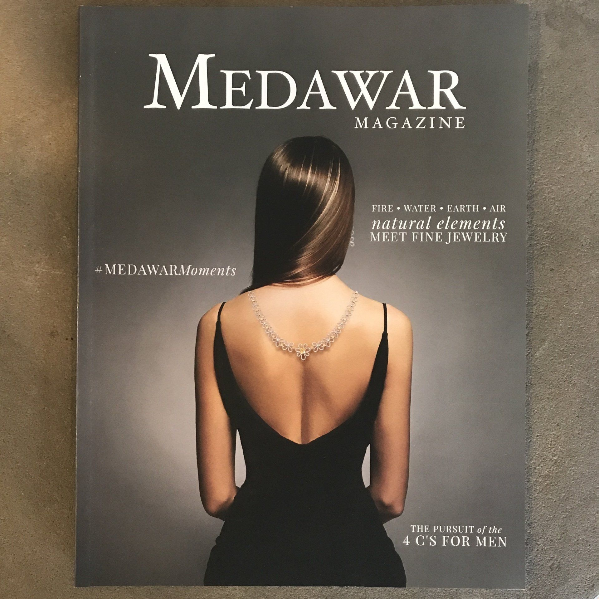 Medawar Magazine cover showing a woman in a black dress from behind, wearing a necklace.