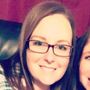 A close up of a woman wearing glasses and smiling.
