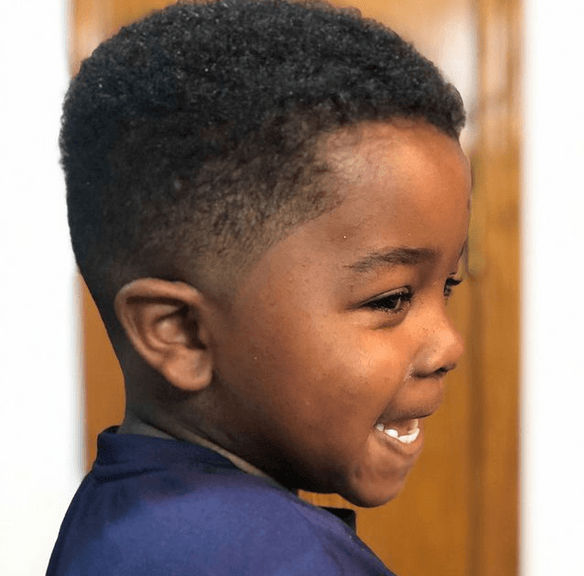 A young boy is smiling and wearing a blue shirt.
