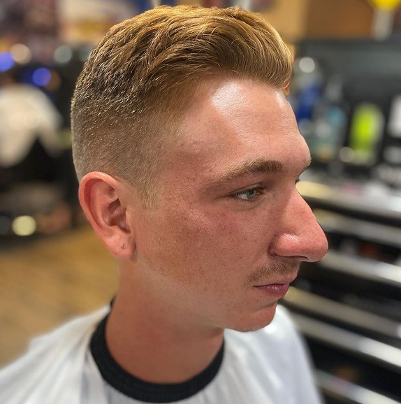 A man is getting his hair cut at a barber shop.
