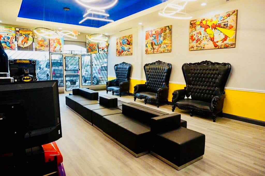 Bright salon waiting area with black chairs, low benches, colorful wall art, and product displays.