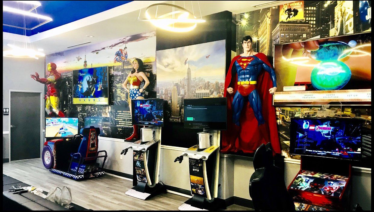 Retro gaming room with multiple arcade cabinets, gaming monitors, and a large Superman statue on display