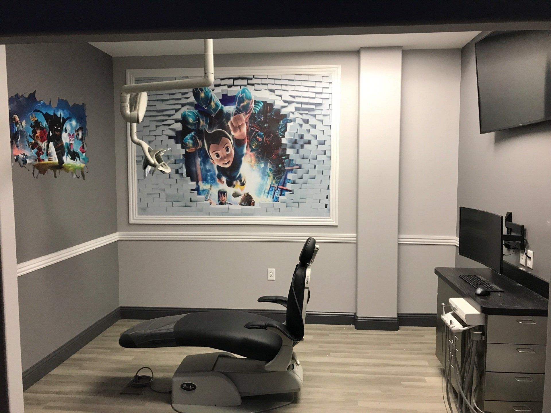 Home gym with black workout bench and machine in a gray basement room with framed wall art and TV