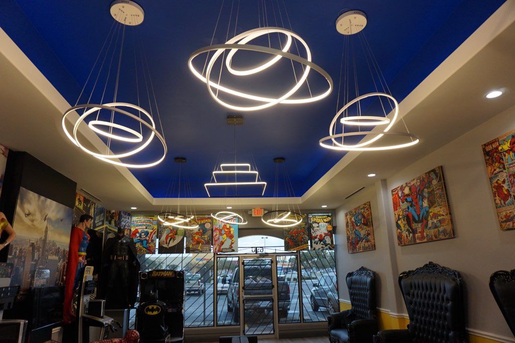 Clothing boutique interior with blue ceiling, hanging ring lights, racks of clothes, and wall art