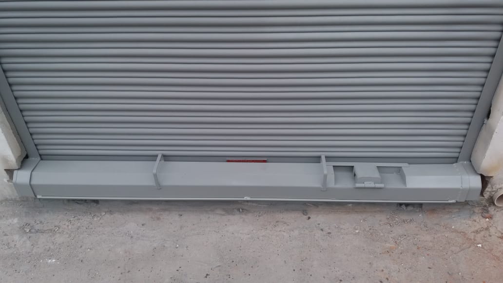 Una persiana metálica enrollable de seguridad de color gris, que se bajaba y que contaba con un mecanismo de barra de bloqueo