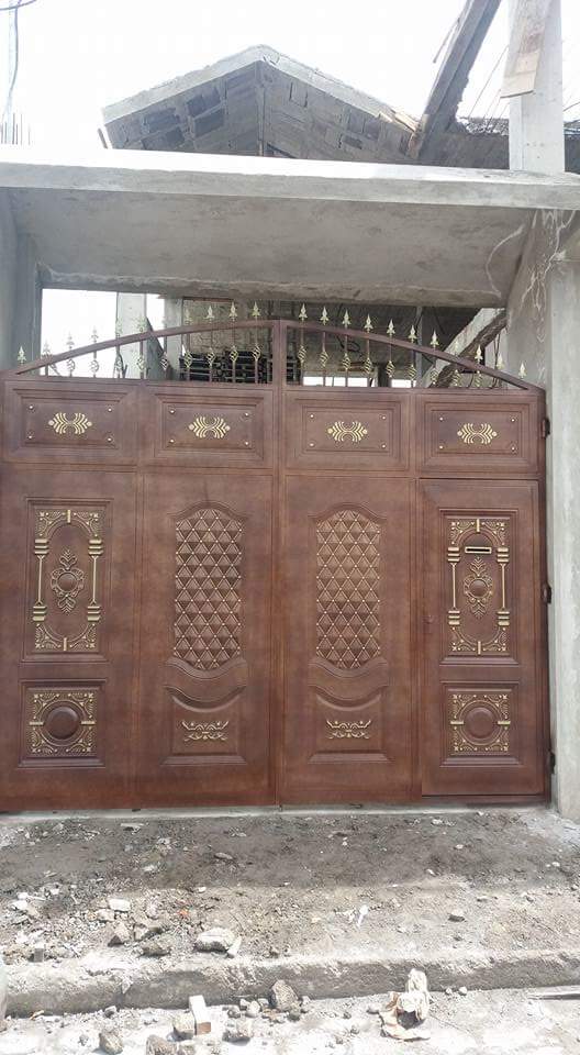 Una gran puerta de metal marrón con intrincados motivos decorativos y una parte superior curvada