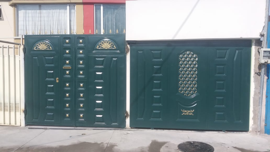 Dos puertas de garaje metálicas de color verde oscuro con detalles decorativos dorados