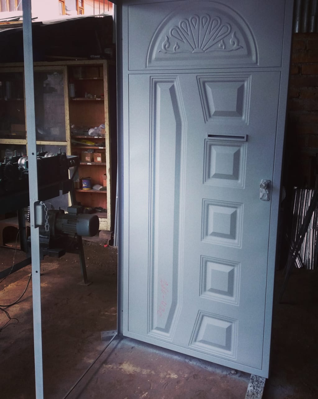 Una puerta de seguridad de acero gris claro con un panel arqueado decorativo y moldura rectangular