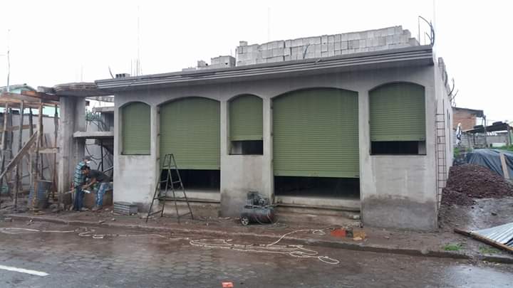 Un edificio de una sola planta en construcción con cinco aberturas arqueadas cubiertas por persianas