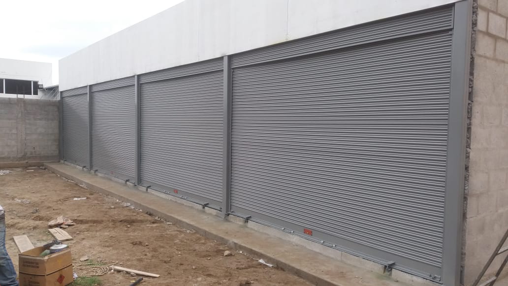 Una larga hilera de persianas de seguridad metálicas grises instaladas en un muro de bloques beige
