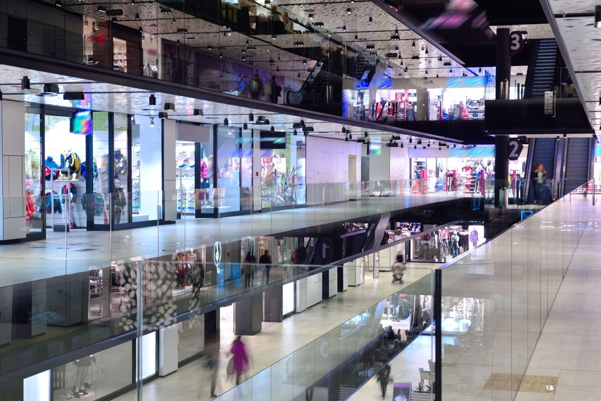 A shopping mall with a lot of shops and people walking around.