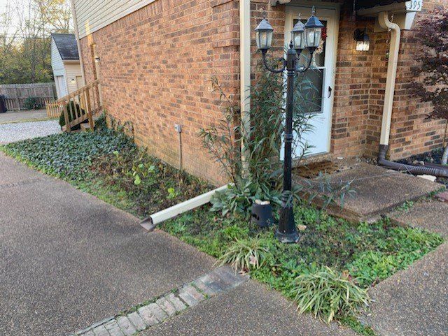 Brick building entrance with overgrown landscaping and a lamppost.