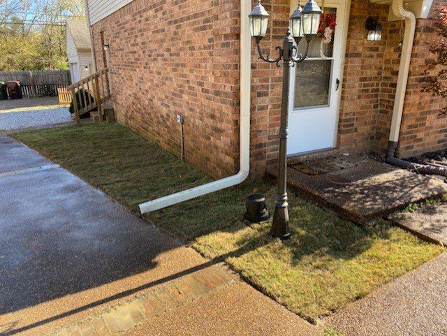 Brick house exterior with green grass, white door, and lamp post.